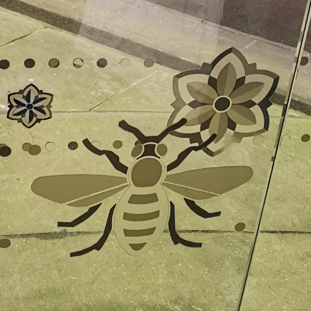 Bee and cotton bud on glass panel at Library Walk