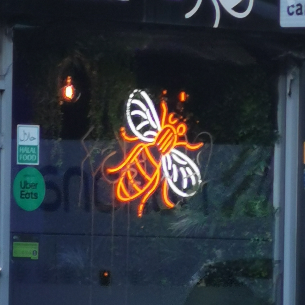 Neon bee in window at 0161 Flamin Grill, Portland Street